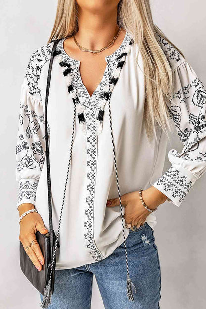 Blusa estampada con mangas abullonadas y lazo con borlas